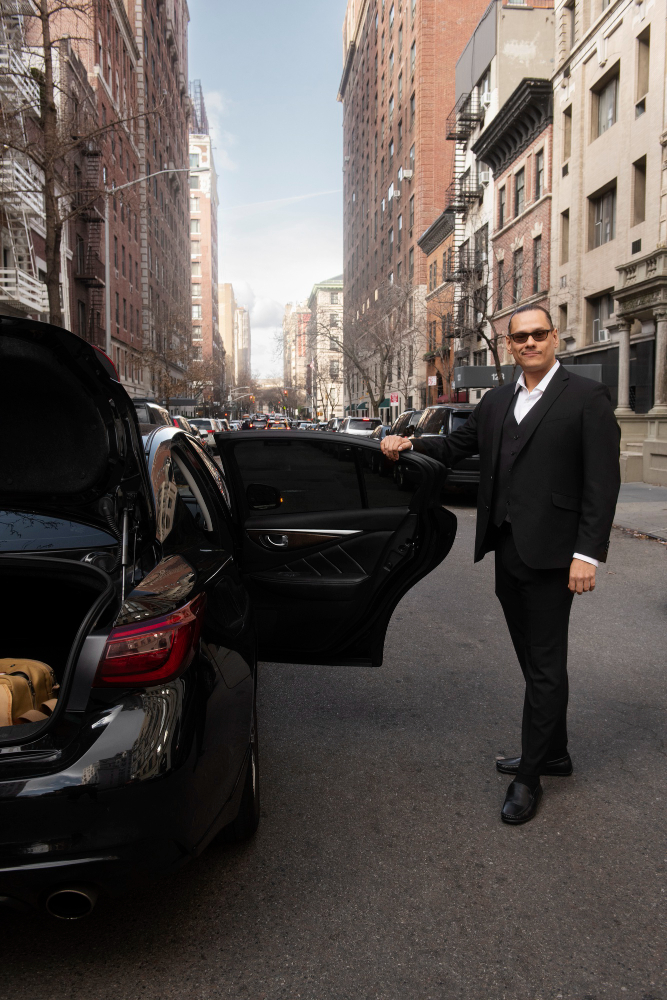 New York chauffeur holding the door of a luxury limousine for passengers.